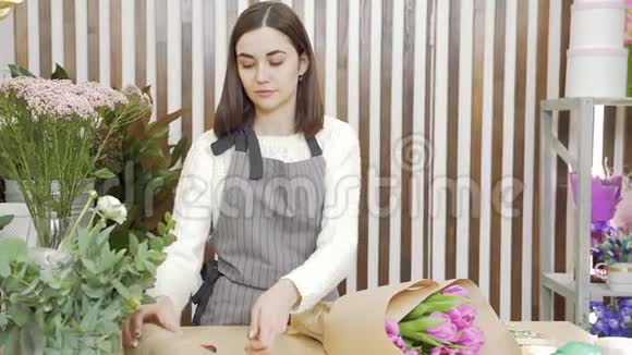 一位年轻的女花商在一家花店或作坊里创作一束郁金香视频的预览图