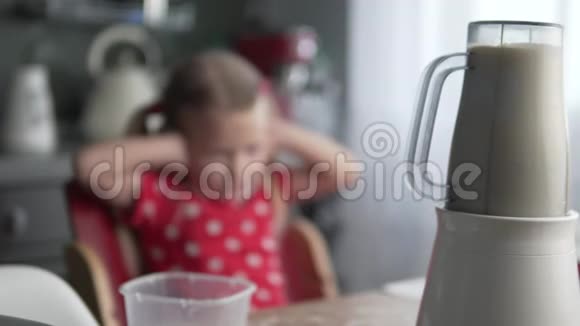 一个小女孩从厨房里一个工作搅拌机的噪音中插入耳朵视频的预览图