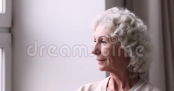 微笑的老奶奶透过窗户享受退休生活视频的预览图