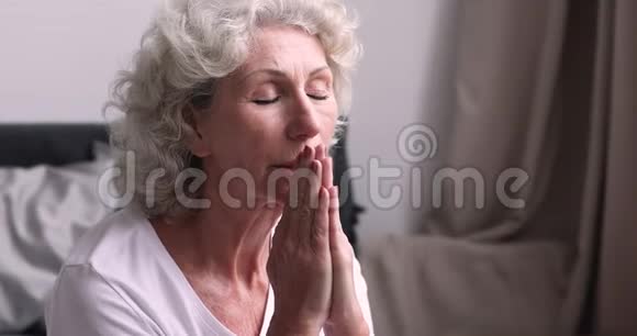 老妇人闭着眼睛在卧室里祈祷闭上眼睛视频的预览图