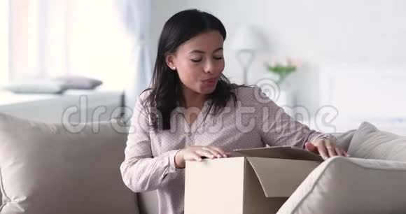 兴奋的非洲女顾客打开包裹箱坐在沙发上视频的预览图