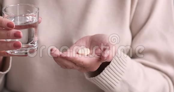 年长的女人手里拿着药丸和一杯水视频的预览图