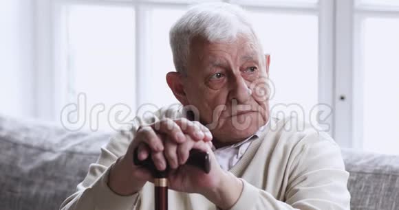 伤心的老爷爷拿着拐杖独自坐在沙发上视频的预览图