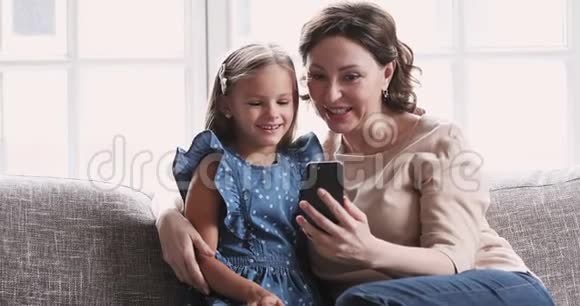 成熟的奶奶在家里用智能手机拥抱孙女视频的预览图