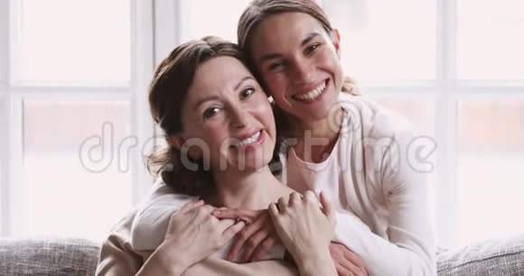 可爱的成年女儿拥抱成熟的妈妈看着镜头视频的预览图