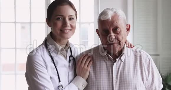 微笑女医生拥抱快乐老年病人看镜头视频的预览图