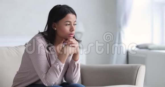 伤心体贴的年轻非洲女人想着问题独自坐着视频的预览图