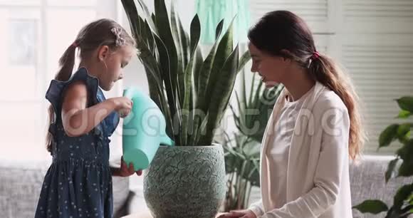 小女孩拿着浇水罐浇水植物帮助妈妈视频的预览图