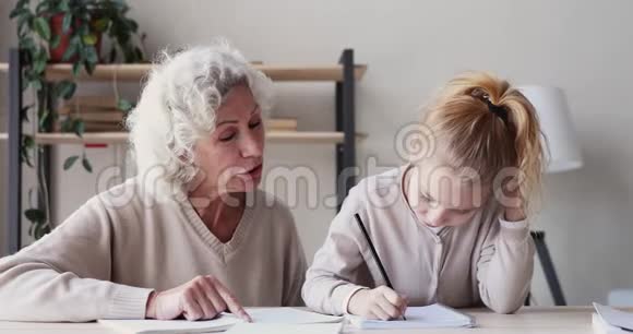 快乐的老奶奶帮助可爱的小孙女做作业视频的预览图