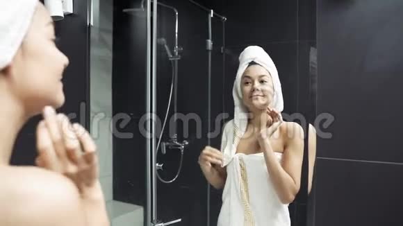 幸福的年轻女人头上有毛巾涂奶油后摸脸视频的预览图