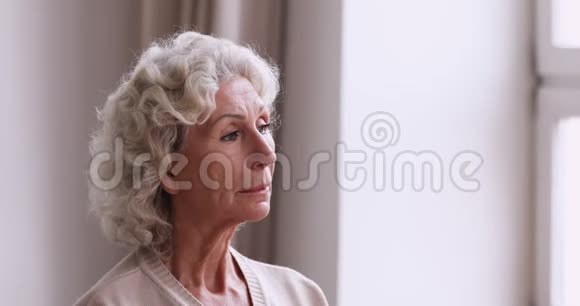 伤心的老奶奶独自站在窗外视频的预览图