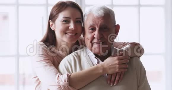 快乐的孙女拥抱高级爷爷拥抱看镜头视频的预览图