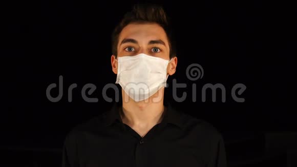戴着医疗面具的年轻人答应了并在黑色背景上点头视频的预览图