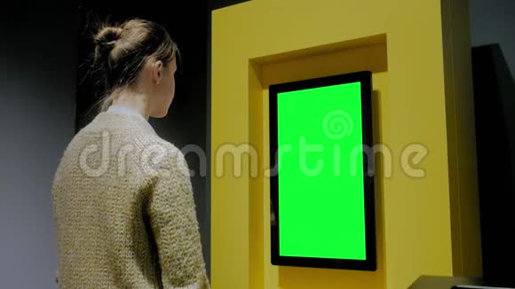 在展览中看到空白绿色展示墙的女人绿色屏幕概念视频的预览图