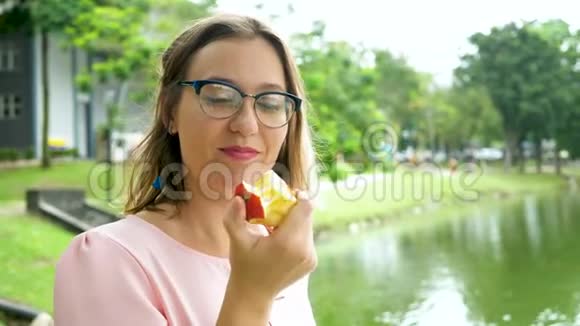 快乐的美女在公园里吃红苹果视频的预览图
