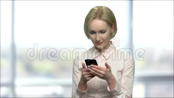 漂亮的金发女人用她的智能手机视频的预览图