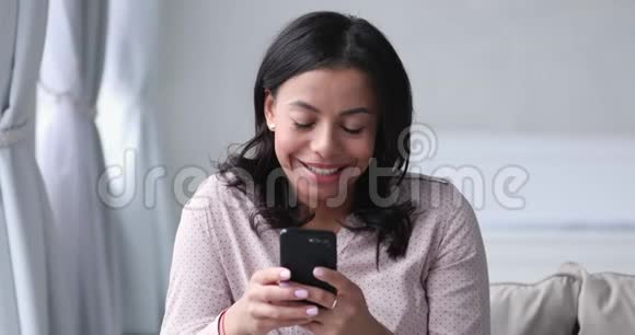 快乐的非洲女人在家里拿着智能手机视频的预览图
