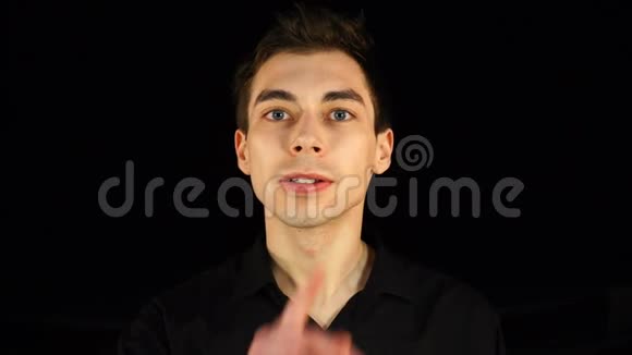 蓝眼睛的男人做了个沉默的手势黑色的背景视频的预览图