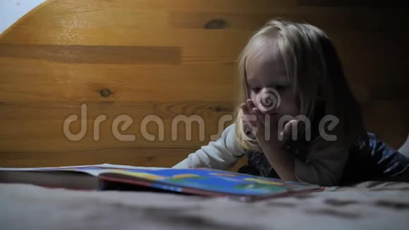 小女孩在一盏灯的灯光下翻阅一本书的书页视频的预览图
