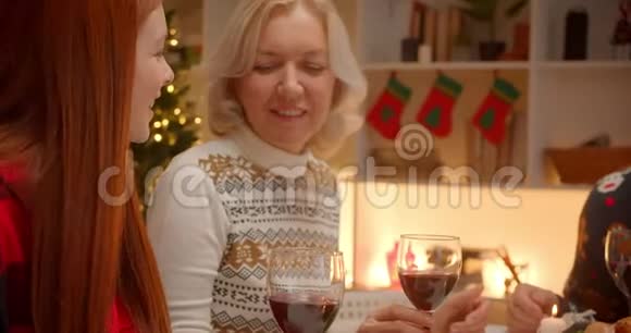 一个金发小女孩晚上在圣诞家庭礼物晚宴上拥抱红发姐姐视频的预览图