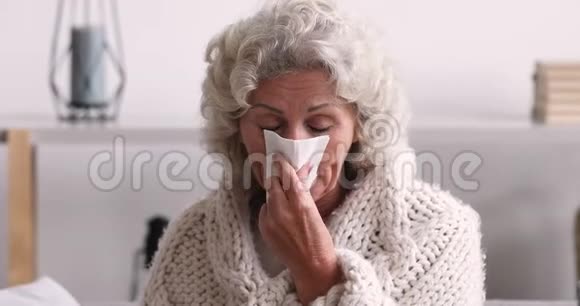 生病的老年妇女用毛毯吹鼻涕视频的预览图