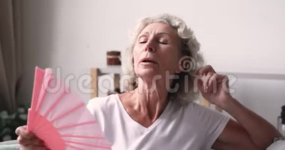 一位在家中挥热扇子的老妇人视频的预览图