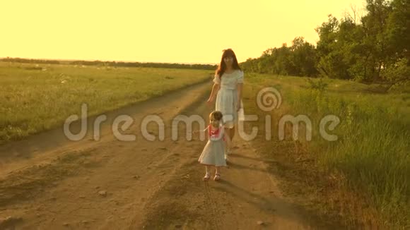 妈妈和宝宝在公园休息快乐童年的概念小女儿和妈妈沿着马路经过田野儿童视频的预览图