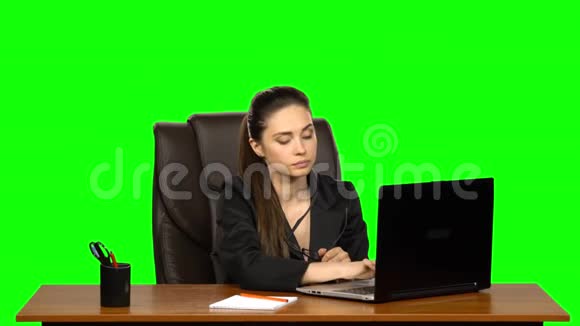 疲惫的女孩手里拿着眼镜在笔记本电脑上工作然后打哈欠绿色屏幕视频的预览图