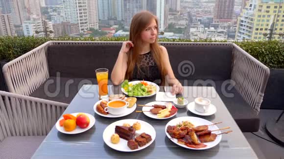 在户外屋顶餐厅女人端着食物和饮料坐在桌子上视频的预览图