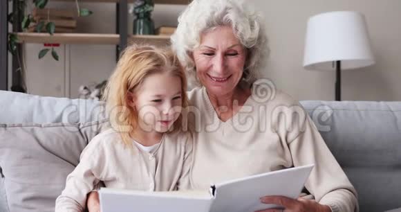 老奶奶看书抱着孙女坐在沙发上视频的预览图