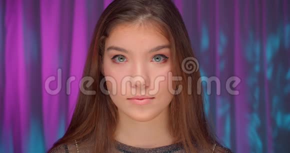 一个穿着霓虹灯的白种人女孩的特写肖像紫色背景自信严肃的表情微笑笑快乐视频的预览图