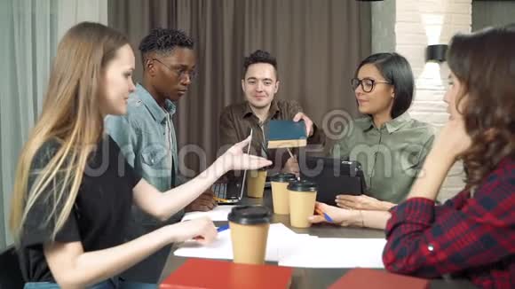 一群多民族的年轻人在一个现代化的办公室或咖啡馆里一起笑一个有趣的笑话视频的预览图