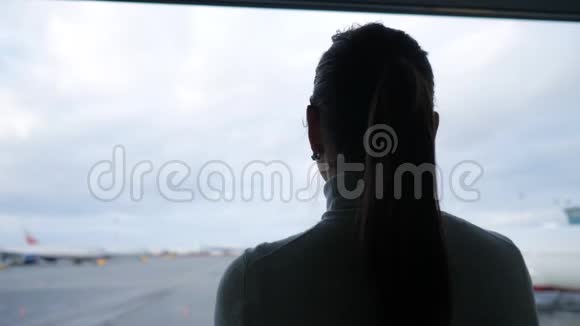 扎着马尾辫的女人看着机场停机坪上的飞机视频的预览图