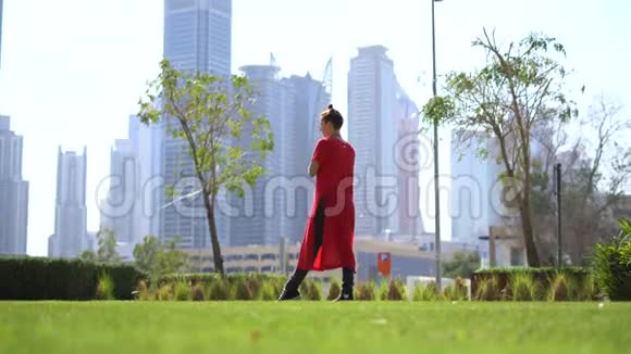 年轻女孩用跳绳在草地上跳跃以迪拜的城市景观为背景视频的预览图