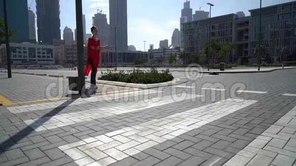 年轻女孩用跳绳在人行横道上跳跃以迪拜为城市背景慢动作视频的预览图