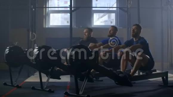 在赛艇机上使用的男性动作缓慢运动员在健身房的排机上锻炼健康的年轻人使用视频的预览图