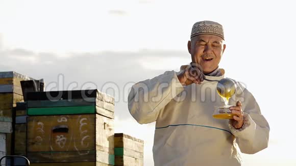 亚洲农场主或微笑老人的画像往容器里倒蜂蜜视频的预览图