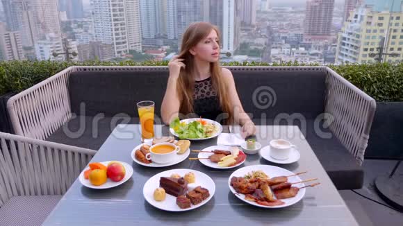 在室外屋顶餐厅妇女坐在桌上享用食物和饮料视频的预览图