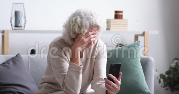 沮丧沮丧的老太太在移动信息概念中读到坏消息视频的预览图