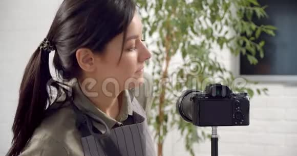 女园丁博主打开相机问候订阅者并录制了一段关于照顾家庭种植的视频视频的预览图