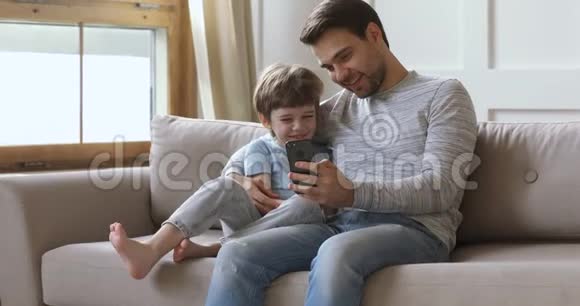 快乐忠诚的爸爸和儿子玩手机游戏视频的预览图