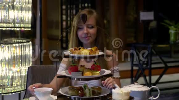 快乐的年轻女人喝杯茶喝附近美味的蛋糕和饼干视频的预览图