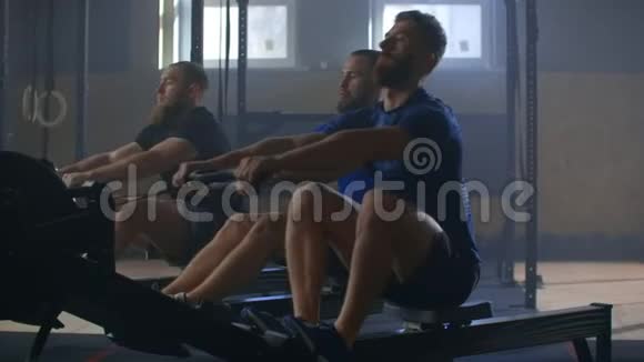 在背部的肌肉上工作三个人在健身房锻炼划船机3男人带着一个运动机视频的预览图