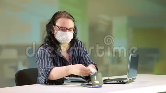 在办公室里一个戴着医用口罩的女人为了预防冠状病毒而消毒这项技术视频的预览图