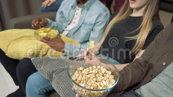 在电视上看电影或连续剧时朋友从一个大透明的碗里拿出爆米花的手视频的预览图