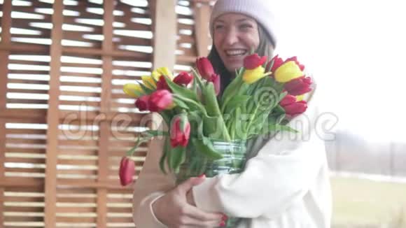 一个带着郁金香花束的快乐女人在街上欢送礼物视频的预览图