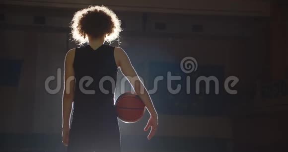 年轻人卷曲篮球运动员黑暗剪影准备光束图像严肃阴影球馆运动视频的预览图