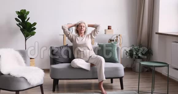 舒适的沙发上放松的快乐安详的老年女性视频的预览图