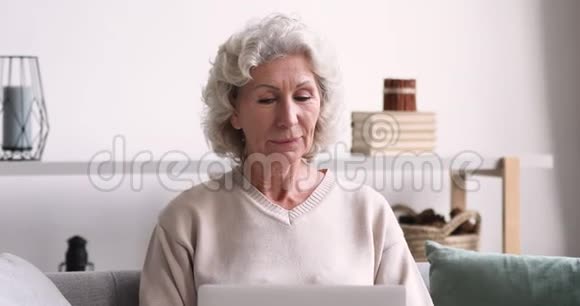 兴奋的老太太在网上的笔记本电脑上获胜视频的预览图