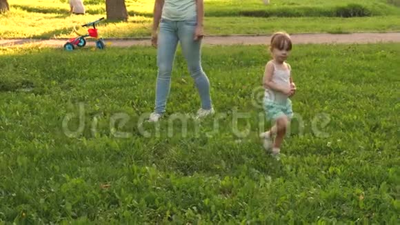 小女儿和妈妈在草坪上公园散步孩子走在绿草上妈妈和宝宝在草坪上休息一种概念视频的预览图